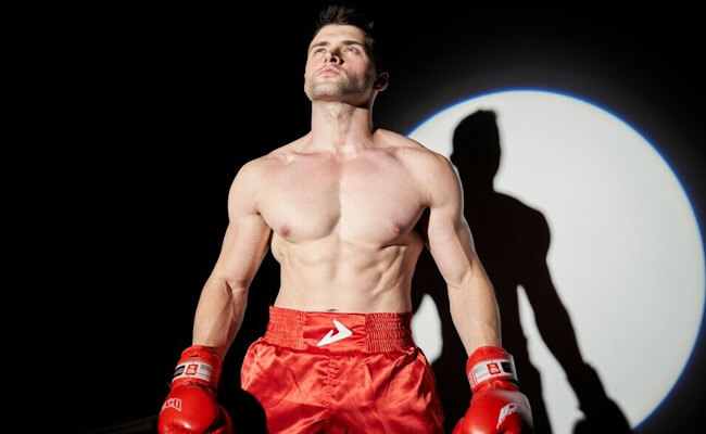 A muscular boxer flexing his abdominal muscles, displaying a well-defined six-pack.