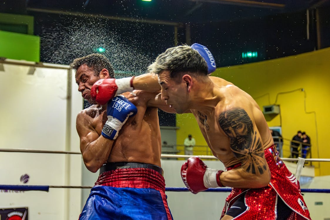 Boxer delivering a powerful punch, sending sweat flying off his opponent in the ring, illustrating the force and impact of punching power.